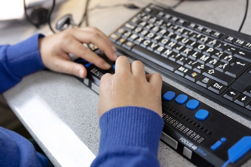 Leerling met een visuele handicap type 6 gebruikt een aangepast toetsenbord
