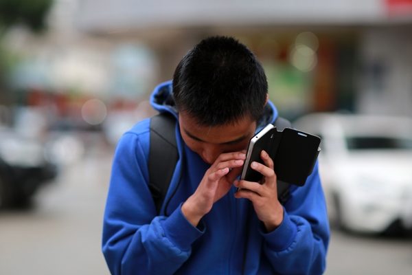 Jonge met visuele beperking gebruikt aangepaste mobile telefoon op straat Jonge met visuele beperking gebruikt aangepaste mobile telefoon op straat