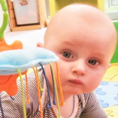 Baby kijkt naar ons achter een gekleurde speeltentje Baby kijkt naar ons achter een gekleurde speeltentje