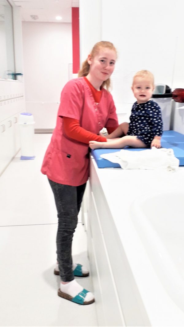 Medewerkster kinderdagverblijf en baby op verzorgingskussen Medewerkster kinderdagverblijf en baby op verzorgingskussen